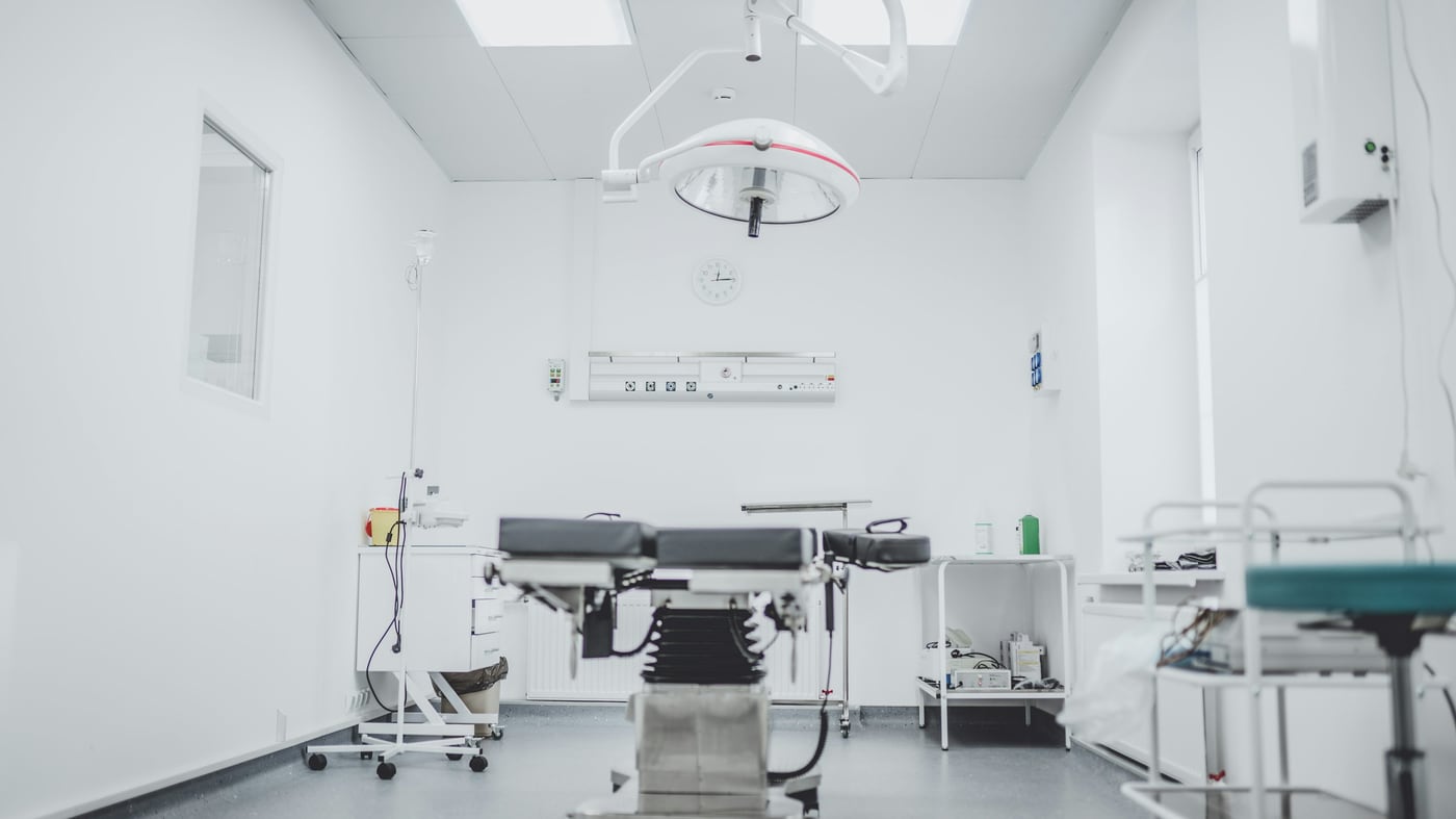 An operating room with a surgical table, overhead light, and medical equipment